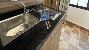 Une cuisine moderne équipée d’un four à micro-ondes, d’un évier à deux bacs et de deux bouteilles d’eau posées sur le plan de travail.