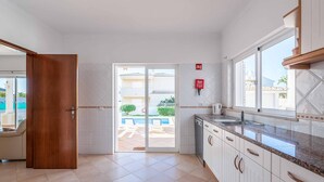 A kitchen with white cabinets, a granite countertop, and a sliding glass door leading to an outdoor area.