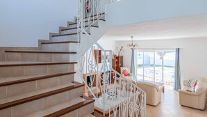 A spacious living area with a staircase leading to an upper floor, a sofa, and a dining table.
