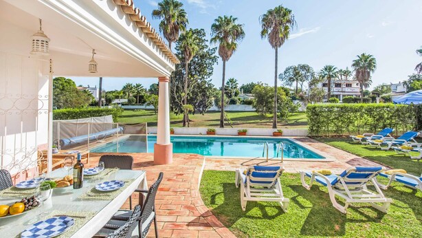 Zona de piscina con un espacio de descanso techado, sillas de salón y una pileta.