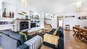 Un amplio salón con chimenea, un sofá, una zona de comedor y una escalera que sube.