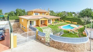 Een gele villa met een zwembad, een overdekte patio en een stenen muur.