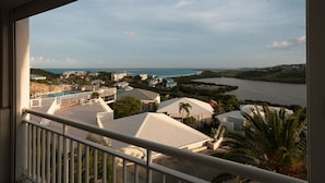 A view from a balcony overlooking a coastal area with houses, a swimming pool, and a body of water. - Magnifique Studio vue mer (Saint martin)