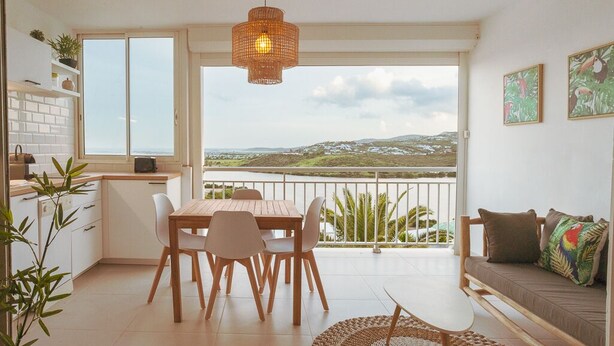 A modern kitchen with a dining area, large windows, and a balcony with a view. - Magnifique Studio vue mer (Saint martin)