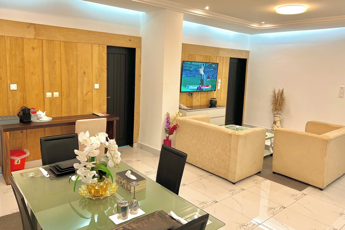 Una sala de estar moderna con una mesa de comedor de vidrio, sofás, un televisor y paneles de madera.