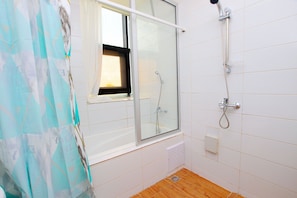 A bathroom with a glass shower enclosure, a window with a view, and a wooden floor. - Appart Hotel Les orchidees (Cotonou)