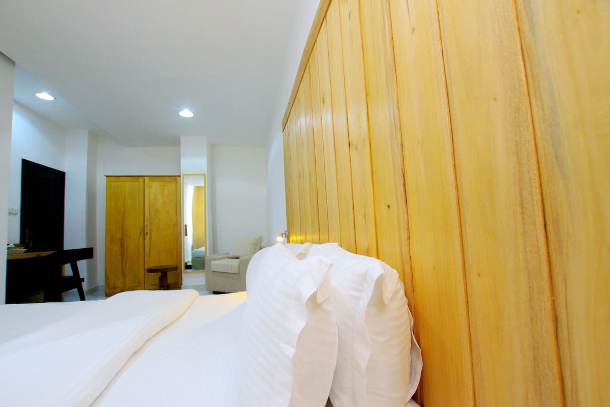 A hotel room with a bed, wooden paneling, a desk with a chair, a television, and a door.