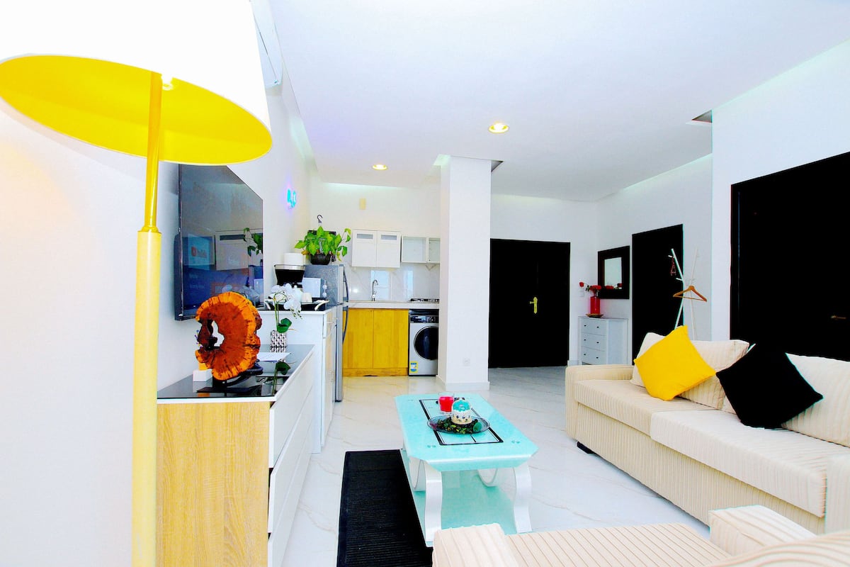 A modern living room with a sofa, coffee table, and a bright yellow lamp.