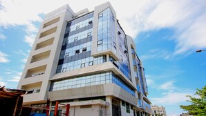 A modern multi-story building with a glass facade and a flat roof. - Appart Hotel Les orchidees (Cotonou)