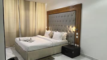 A neatly made bed with white linens, a headboard with a tufted design, and a bedside table with a remote control.