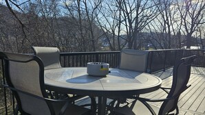 A round outdoor table with chairs, surrounded by a wooden deck. - Cozy, private apt in small river town with short drive to city-border WI and IA. (Brownsville)
