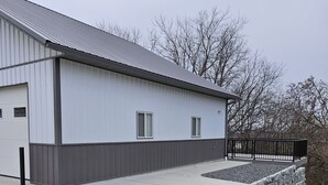 A single-story industrial building with a flat roof, a concrete driveway, and a small grassy area in front. - Cozy, private apt in small river town with short drive to city-border WI and IA. (Brownsville)