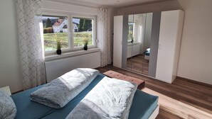 A modern bedroom with a bed, a window, and a wardrobe.