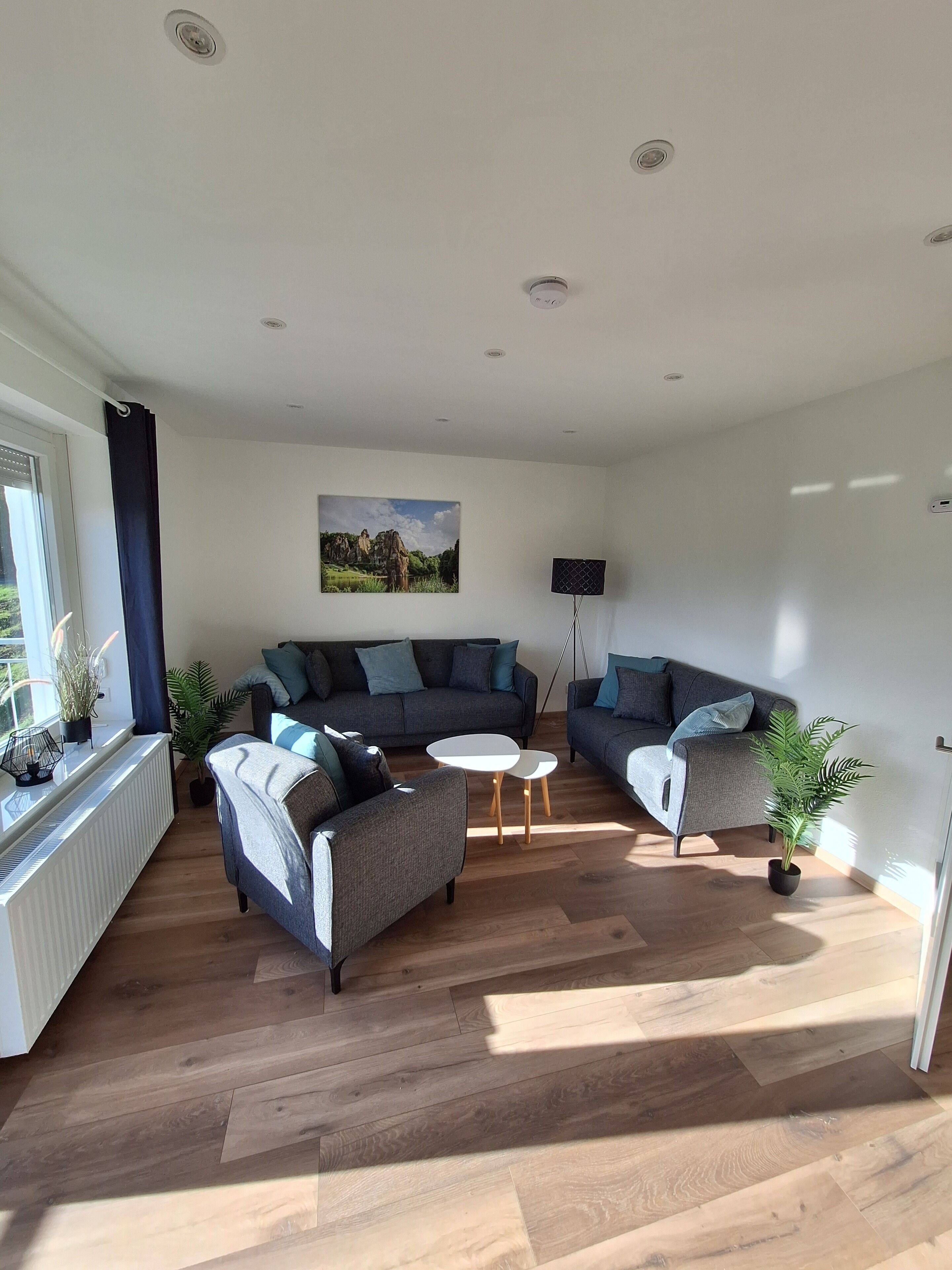 A modern living room with a grey sofa set, a small white table, and a floor lamp.