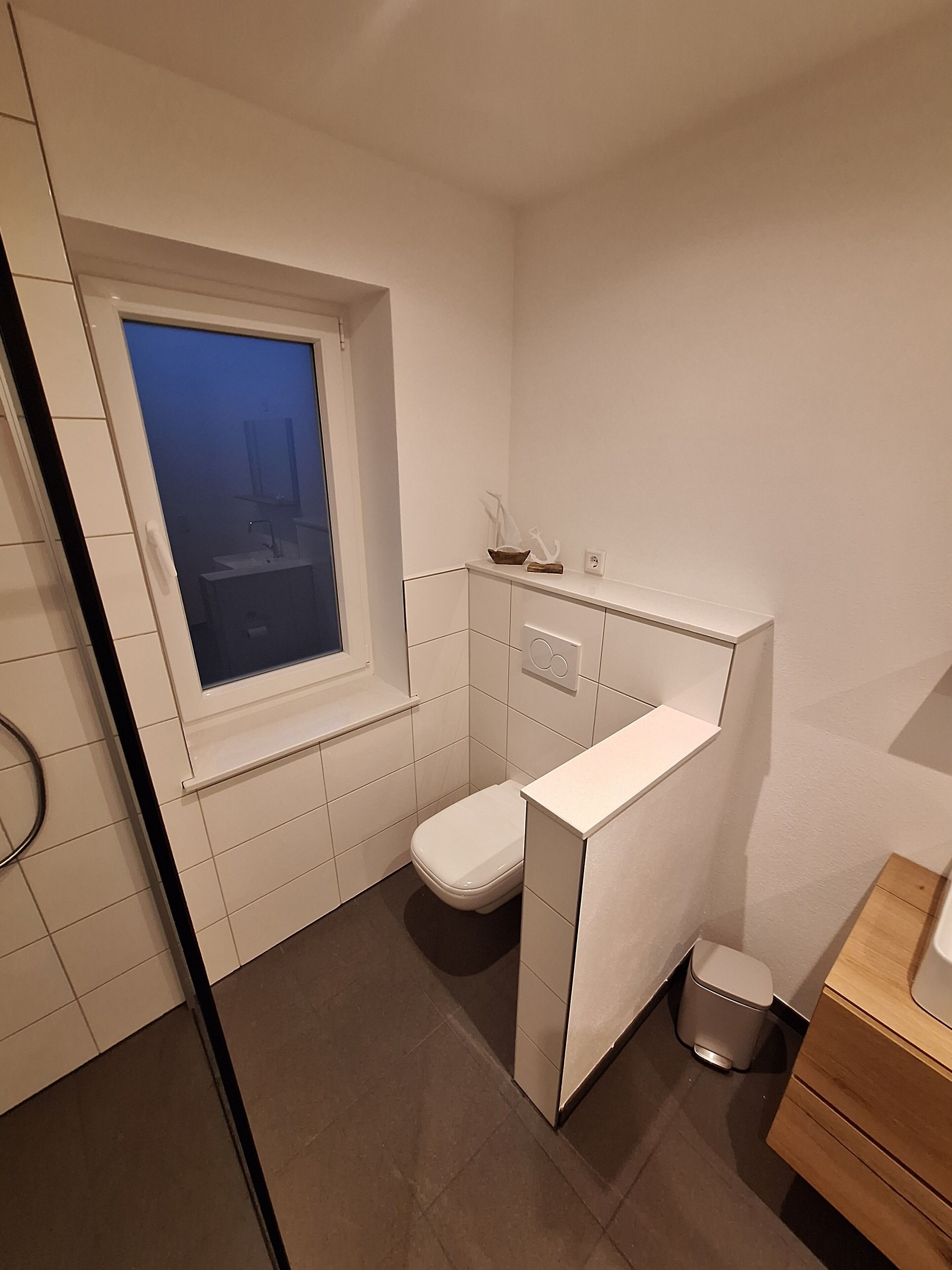 Een compacte, moderne badkamer met toilet, wastafel en raam.