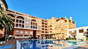Un hôtel doté d’une piscine, de plusieurs balcons et d’une allée dallée.