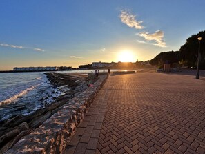 Walking along the paved promenade, enjoy the serene views of the ocean and the distant building complex.