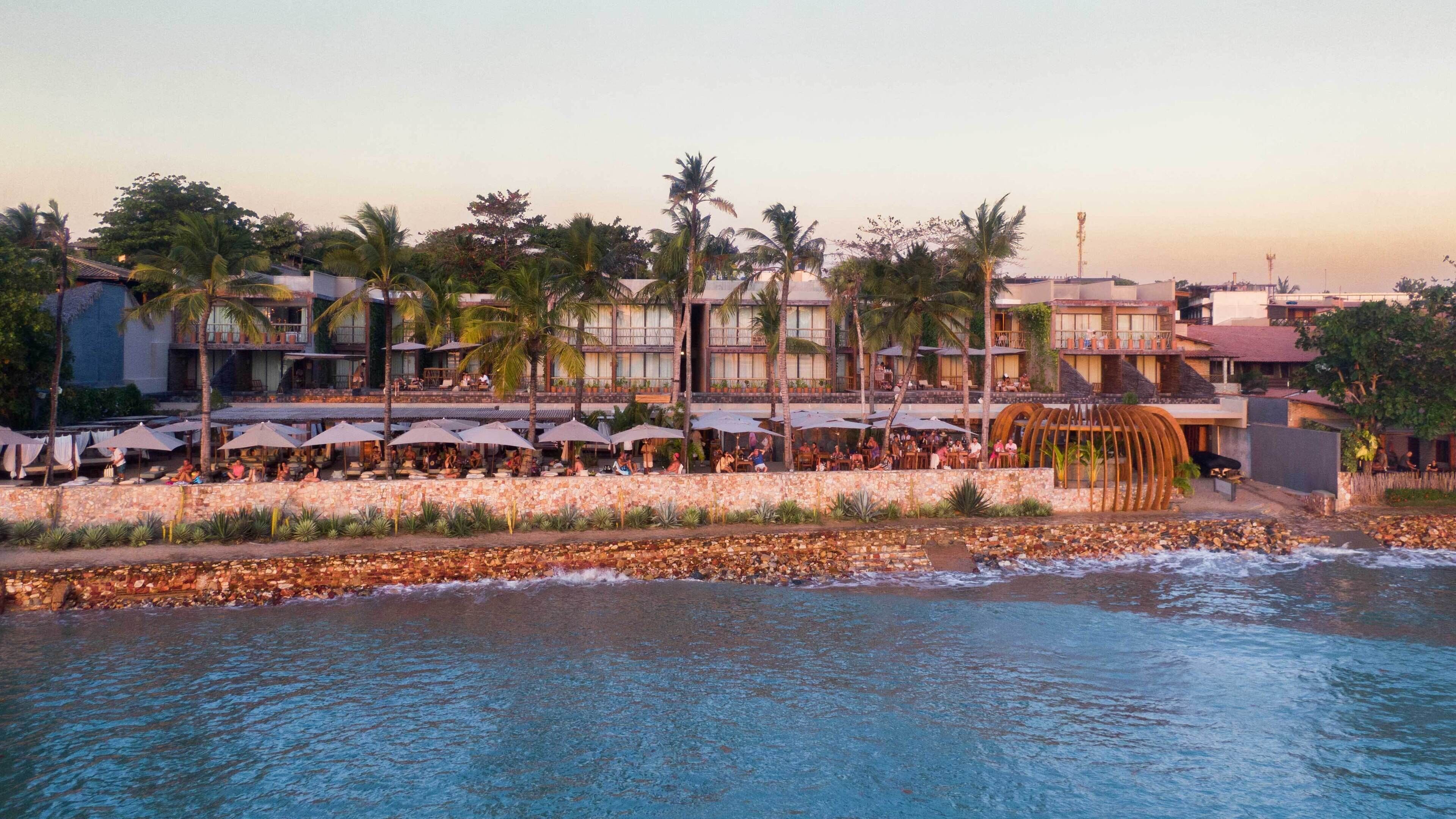 Un hôtel situé sur la côte, doté d’une terrasse et offrant une vue sur la mer.