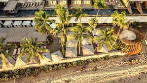 Vista aérea de un resort con varias piscinas, palmeras y áreas con sombra y sombrillas.