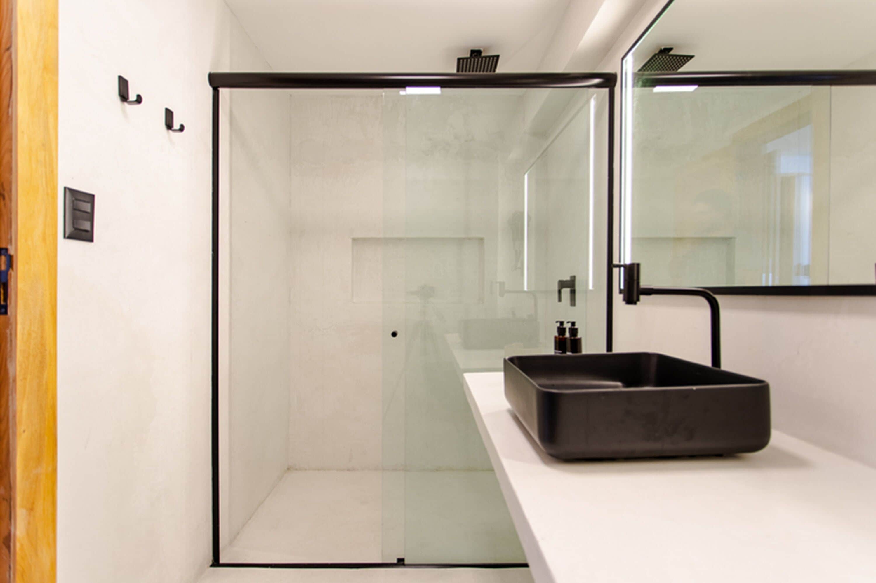 A modern bathroom with a glass-enclosed shower, a black sink, and a large mirror.