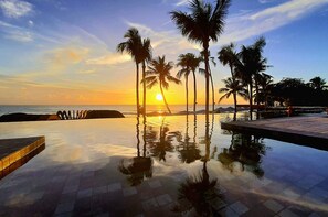 A reflective infinity pool with palm trees and a sunset view. - Apenunga Eco Hotel (Jijoca de Jericoacoara)
