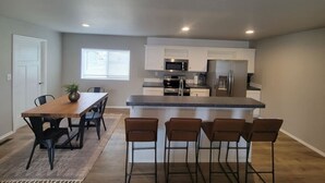 Een moderne keuken met een centraal eiland, roestvrijstalen apparatuur en barstoelen.