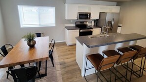 Een moderne keuken met witte kasten, een granieten aanrechtblad en een centraal eiland met barstoelen.