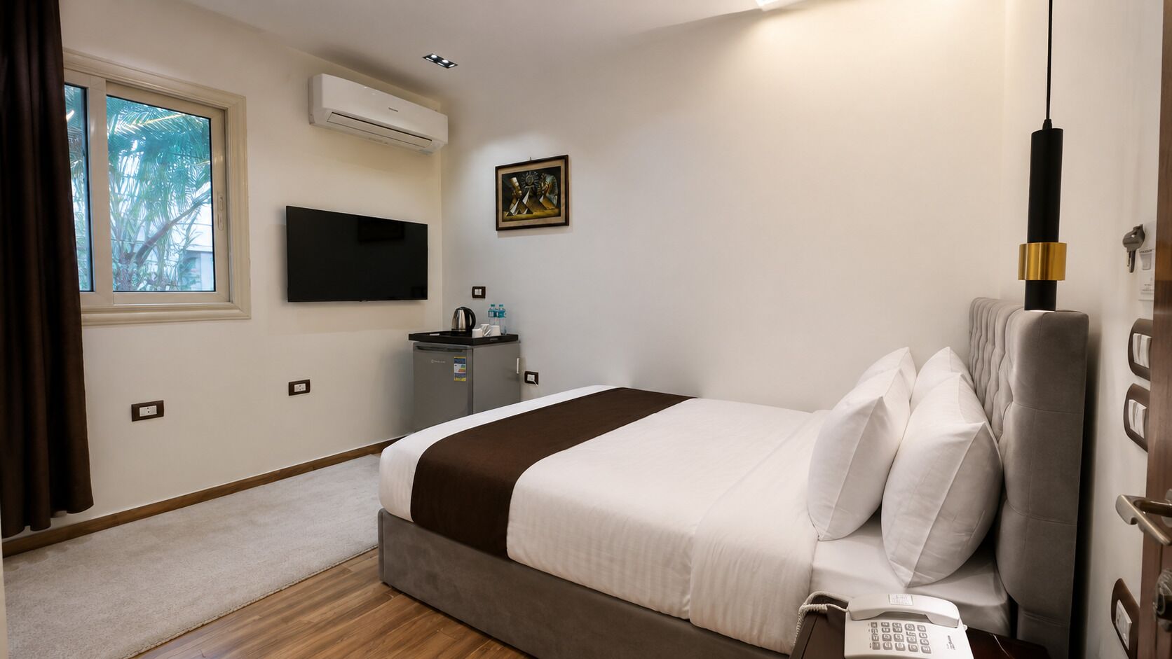 Een hotelkamer met een bed, een televisie, een klein bureau en een raam met gordijnen.