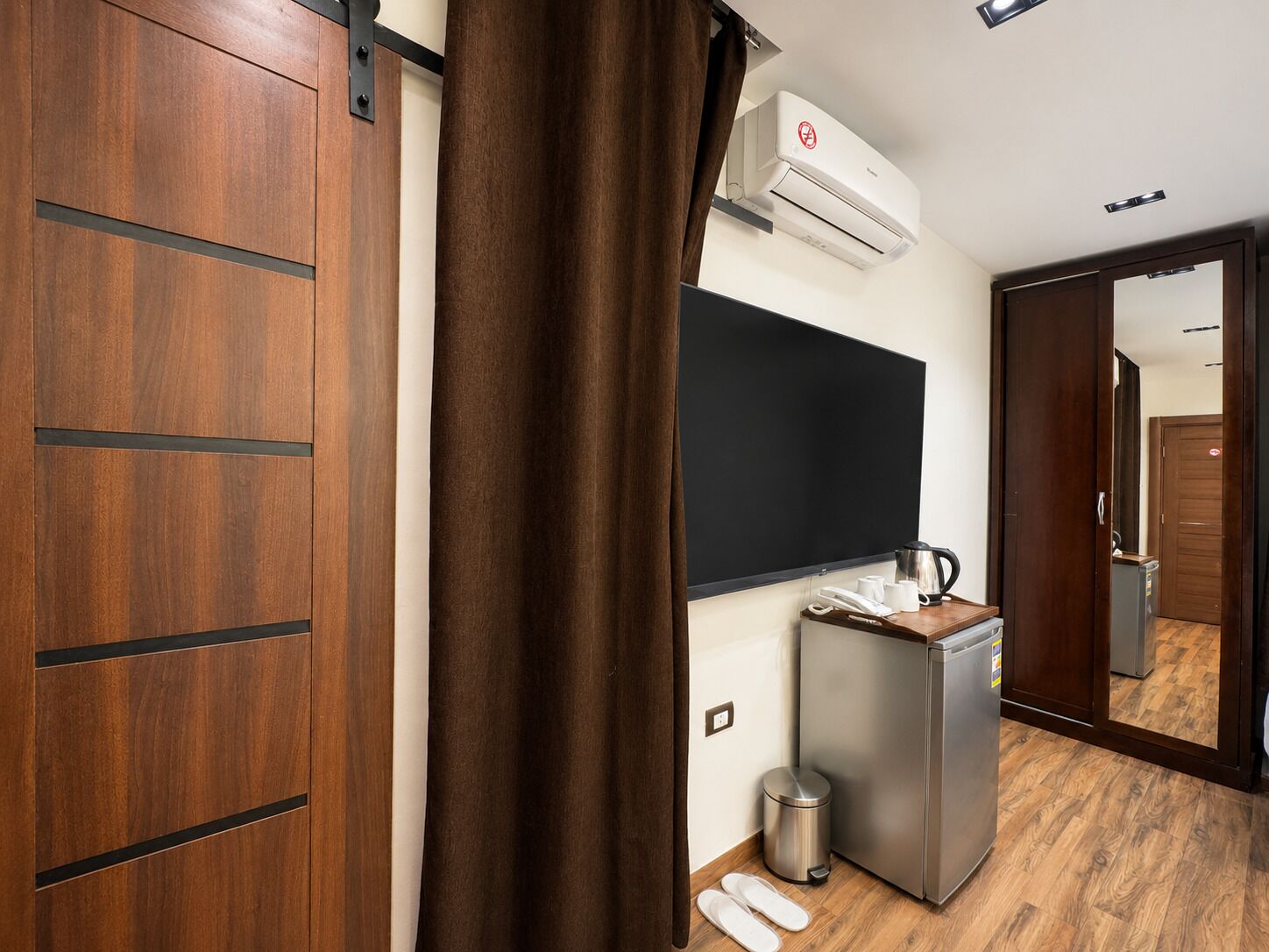 Ein Hotelzimmer mit einem Holzschrank, einer Tafel, einer Küchenzeile und einem Spiegel.