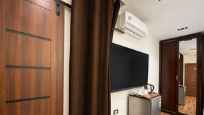 Een hotelkamer met een houten kast, een schoolbord, een kitchenette en een spiegel.