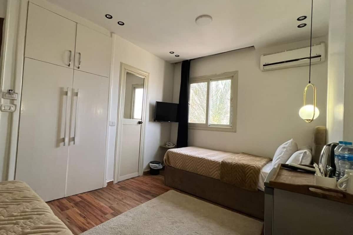 A compact hotel room with a bed, a desk with a chair, a TV, and a window.
