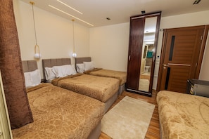 Ein Hotelzimmer mit drei Betten, einer Holztür und einem Spiegel, der das Badezimmer widerspiegelt.