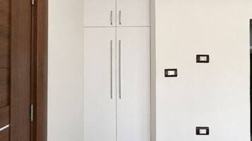 Une armoire blanche à deux portes et un plancher en bois.