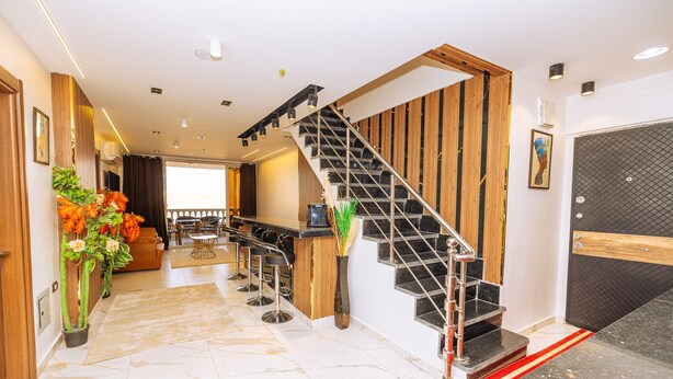 A hotel lobby with a marble floor, a staircase, a reception desk, and a bar area.