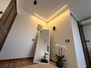 A modern interior with a wooden door, a mirror reflecting a bed, a potted orchid, and recessed lighting. - White Pyramids inn  (Giza)