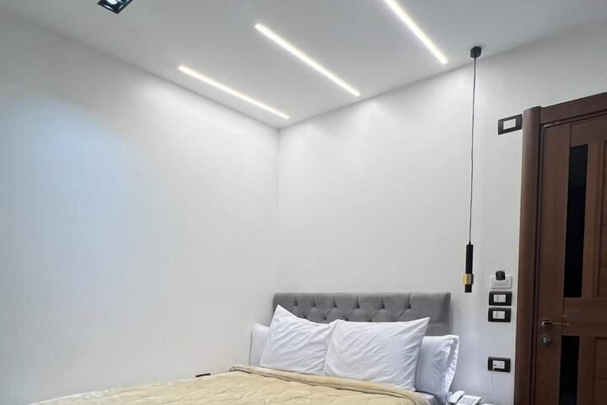 A bedroom with a bed, bedside table, and a wooden door.