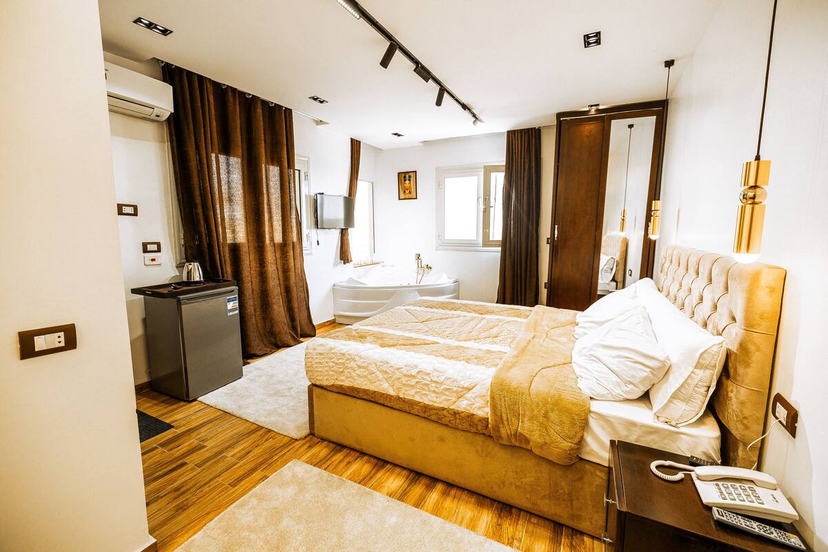 A modern hotel room with a bed, bedside table, and a desk with a telephone.