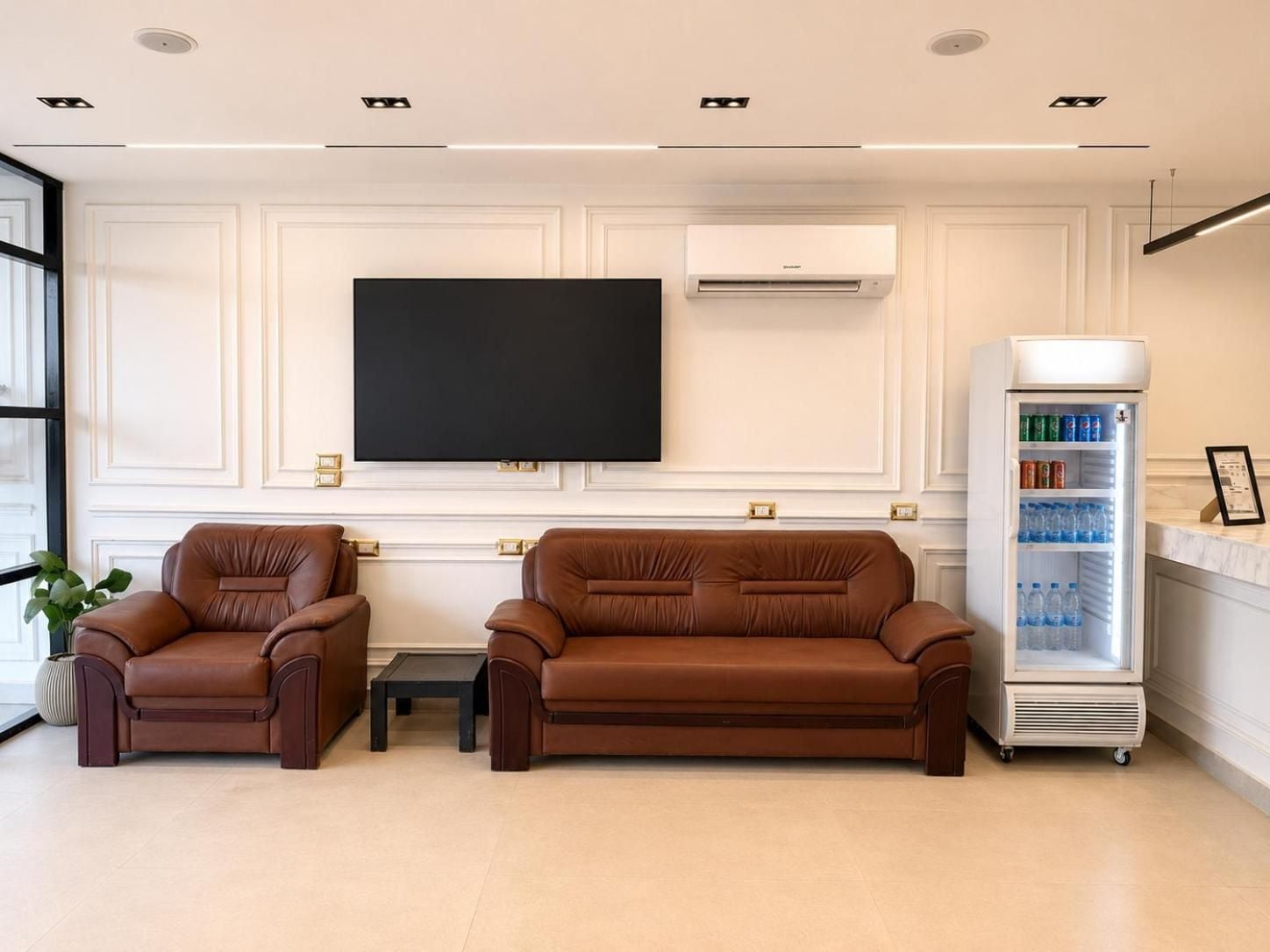 Habitació moderna amb dos sofàs de pell, televisió de pantalla plana, aire condicionat i barra minibar.