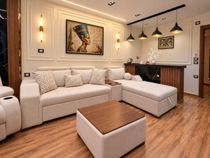 A modern living room with a sectional sofa, a wooden coffee table, pendant lighting, and artwork on the wall. - White Pyramids inn  (Giza)