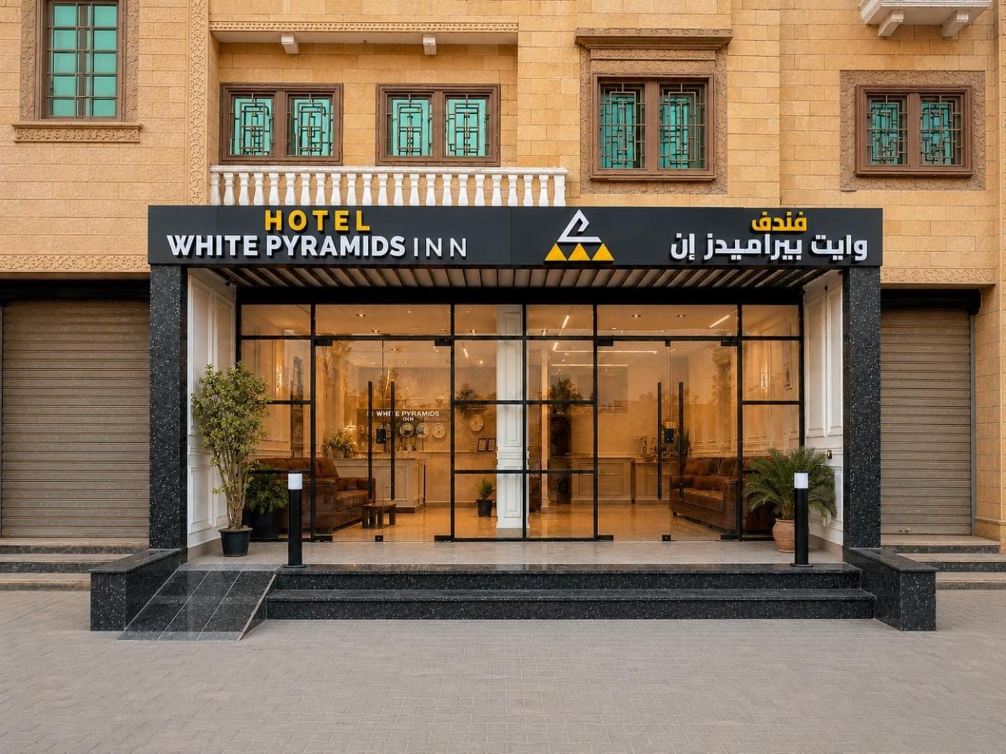 L’entrée d’un hôtel, avec une enseigne indiquant « WHITE PYRAMIDS INN » et un texte en arabe.