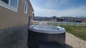 A hot tub outside a building with a view of mountains and a white fence. - Our new lovely home ready for you (Garden City)