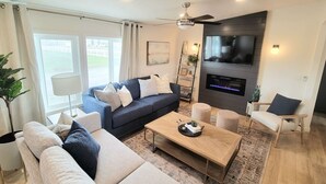 A modern living room with a sofa, coffee table, and a TV mounted on the wall. - Our new lovely home ready for you (Garden City)
