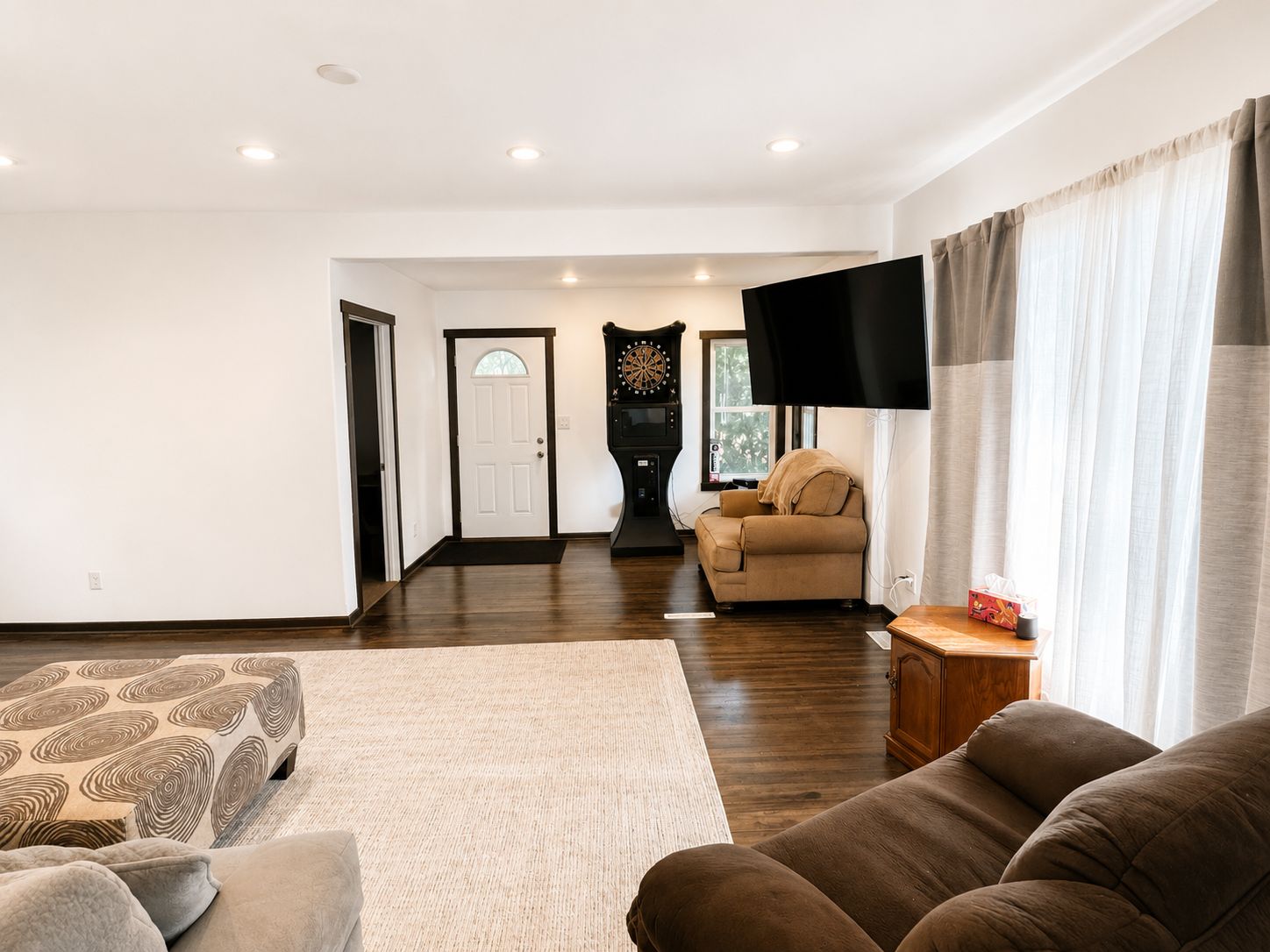 Een woonkamer met een bank, een televisie en een deur naar een andere kamer.