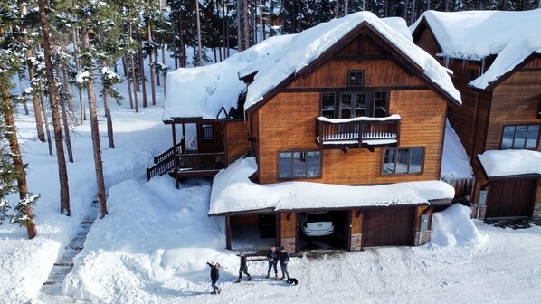 Eine Holzhütte mit einem Balkon, umgeben von schneebedeckten Bäumen.