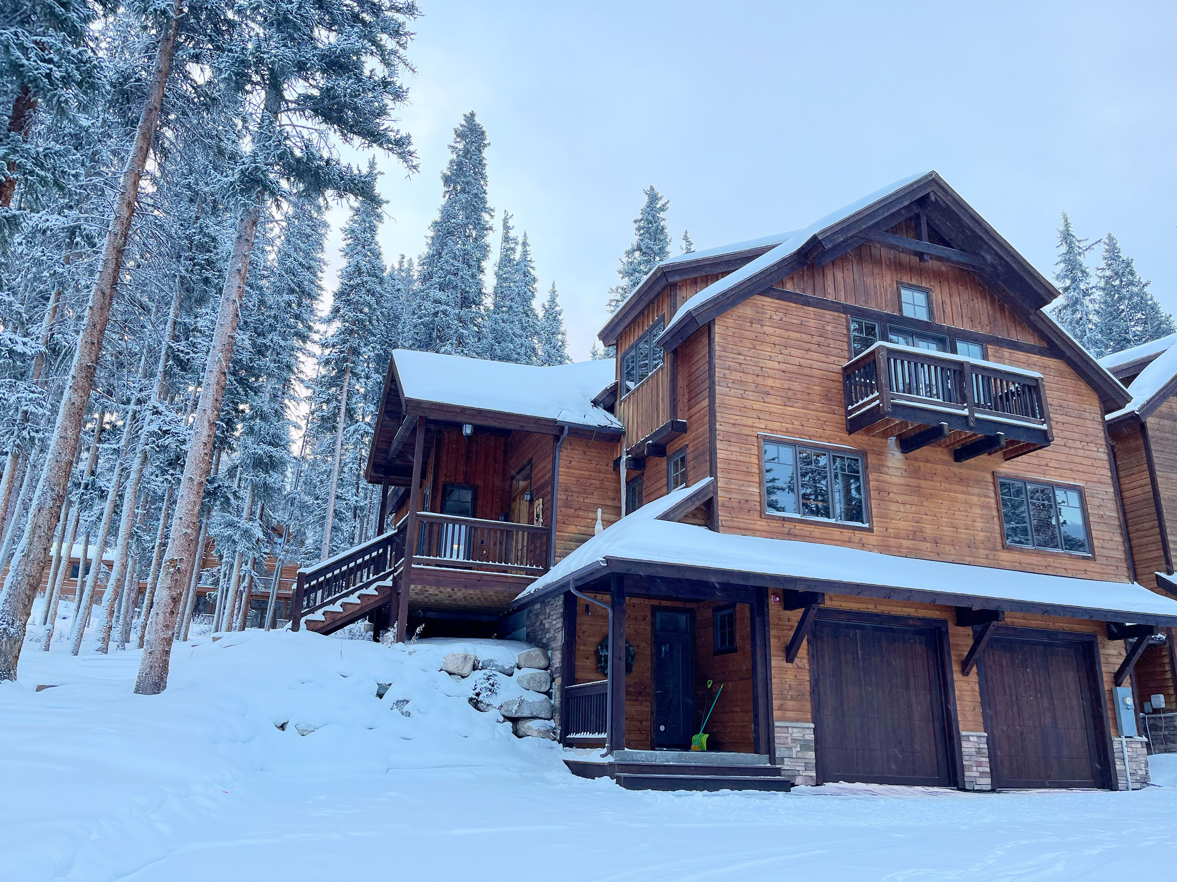 A multi-story wooden cabin with a balcony, surrounded by snow-covered trees.