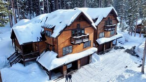Eine Holzhütte mit Balkon, umgeben von schneebedeckten Bäumen.