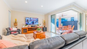 Una sala de estar con televisor, sofá y un comedor con sillas y una mesa.