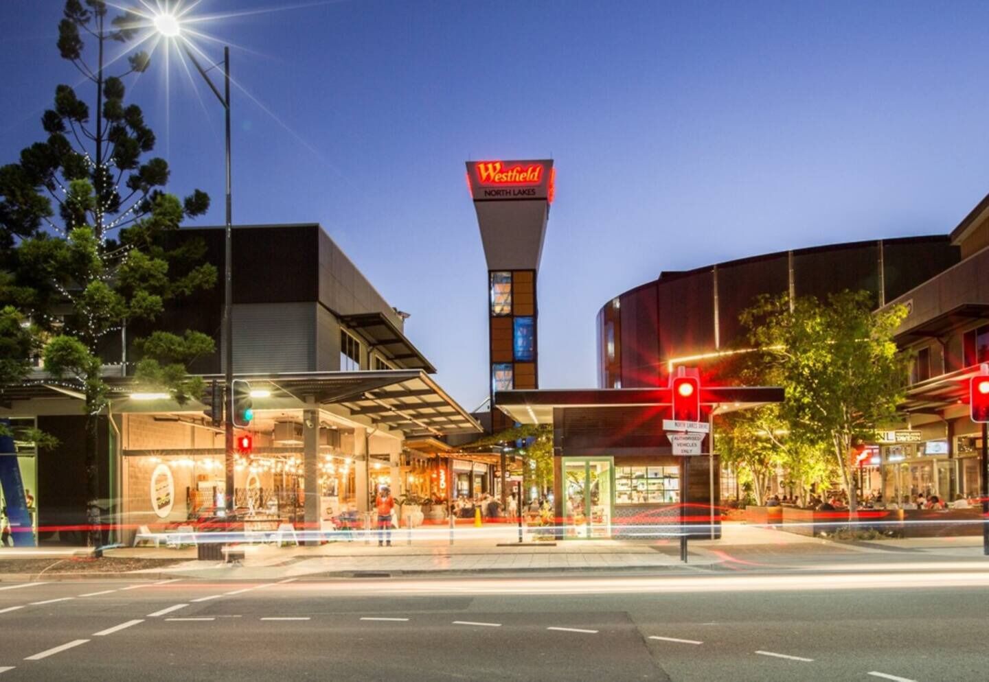 Un centro comercial Westfield con un letrero llamativo, asientos al aire libre y un paso de peatones.