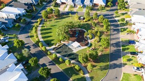 Vista aérea de un barrio residencial con casas, calles y un parque infantil.