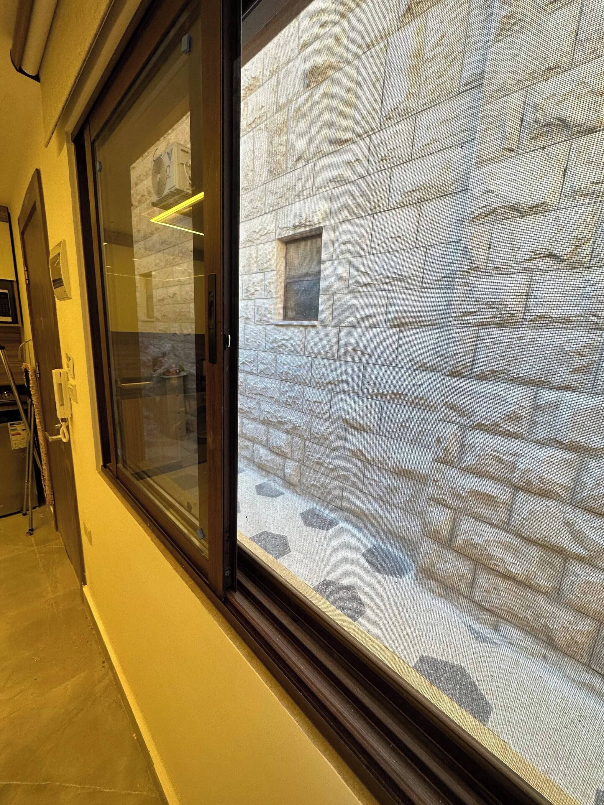 A hotel entrance with a glass door, a stone wall, and a small window.